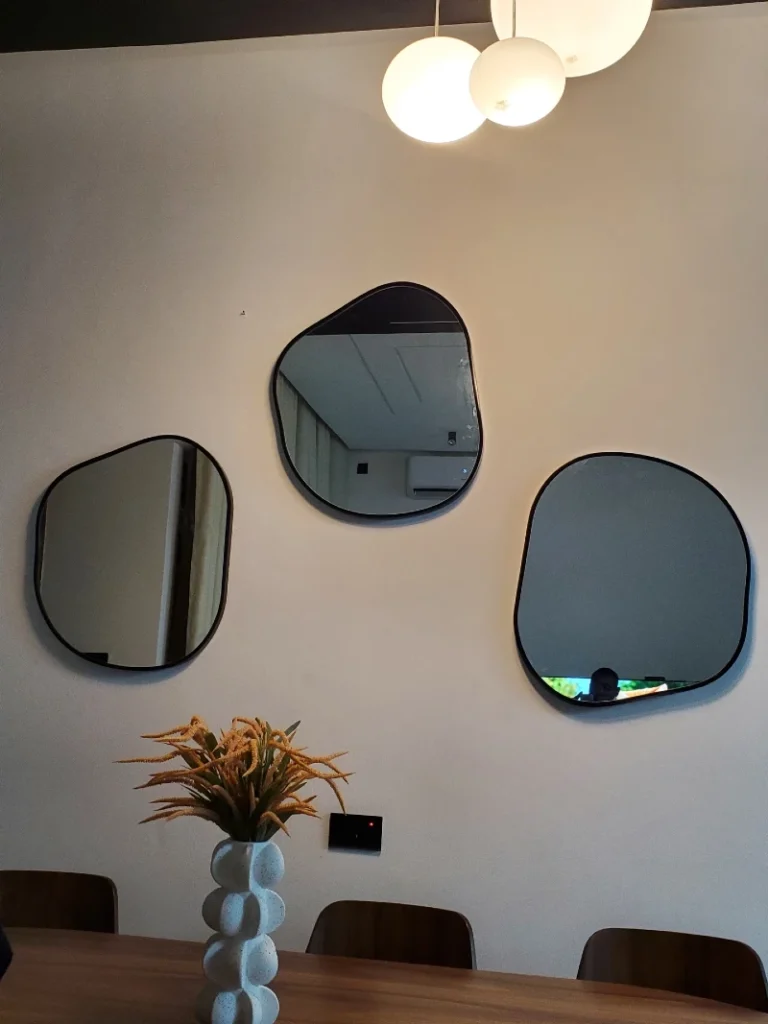 9. Three Organic Black Mirrors Above a Wood Dining Table and Bubble Vase