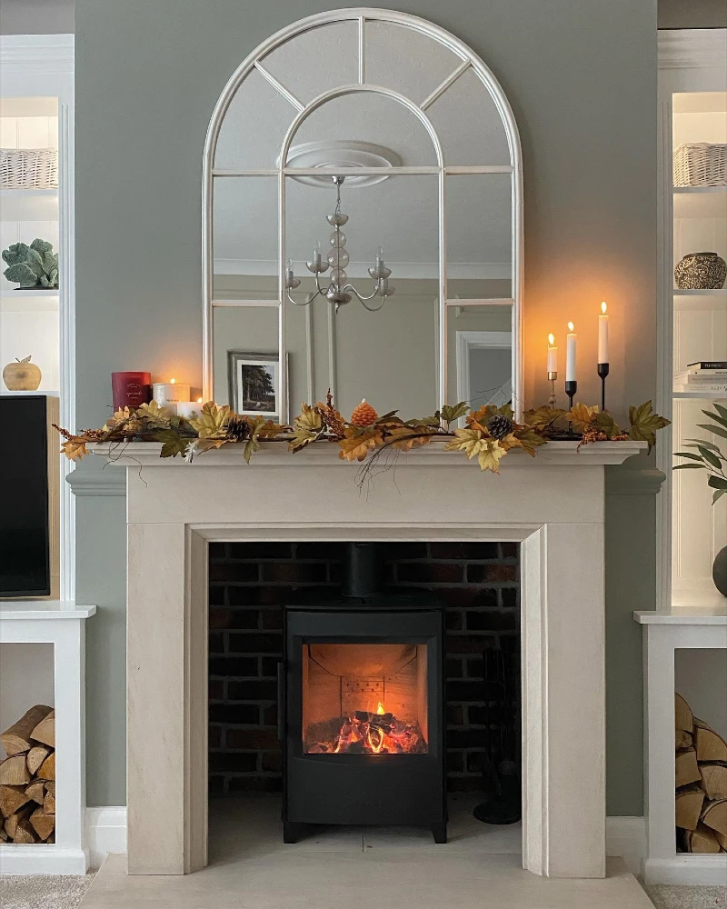 Arched Windowpane Mirror with Autumn Leaf Garland, Black Candleholders, and Wood Stove Glow