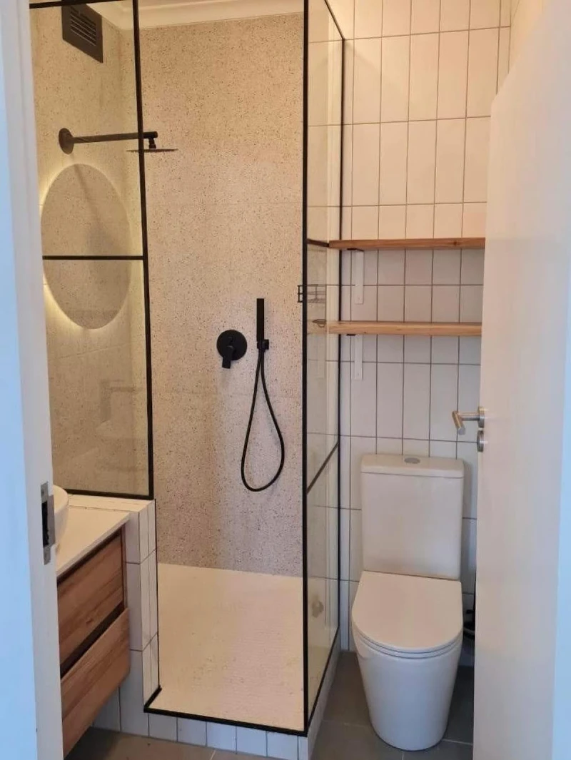 Black Grid Glass Shower Enclosure with Speckled Stone Tile and Vertically Stacked Grid Backsplash