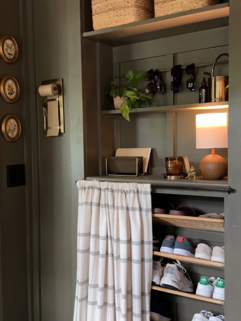 Built-In Olive Green Nook with Slanted Wooden Shoe Shelves and Cafรฉ Curtain