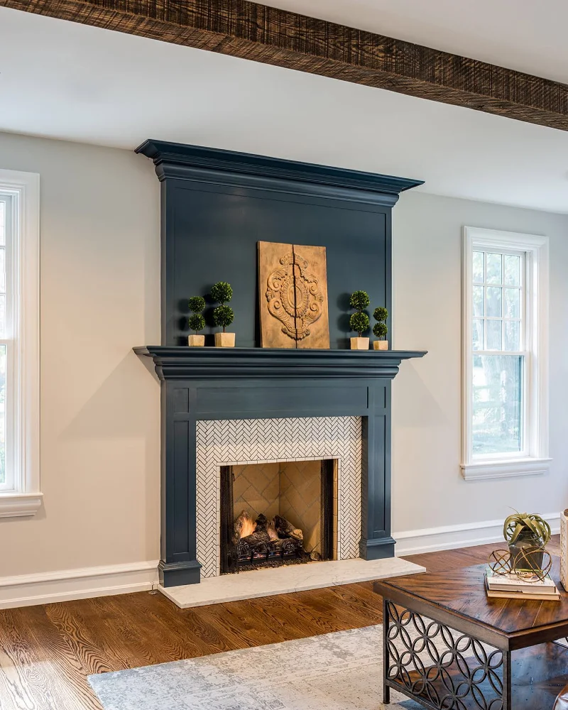 Charcoal Blue Fireplace Wall with Herringbone Tile, Carved Wood Panel, and Topiary Pairs
