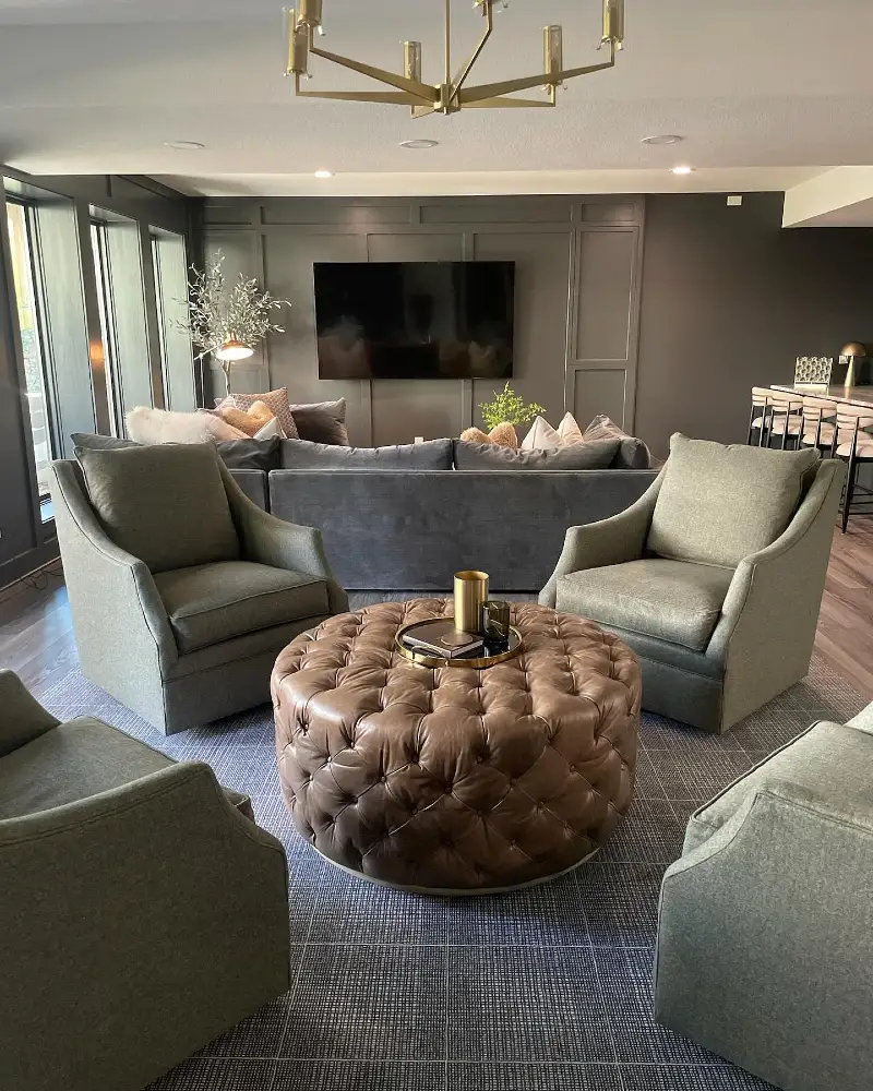Charcoal Board and Batten Accent Wall with Tufted Brown Leather Ottoman and Sage Swivel Chairs