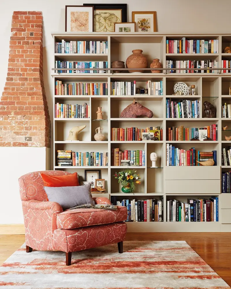 Cream Built In Library Wall with Brick Chimney and Coral Patterned Armchair
