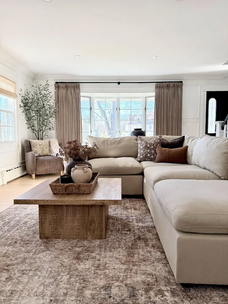  Cream Sectional with Taupe Drapes, Woven Tray, and Block Wood Coffee Table