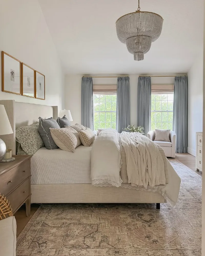 Cream Wingback Bed with Dusty Blue Drapes and Beaded Chandelier