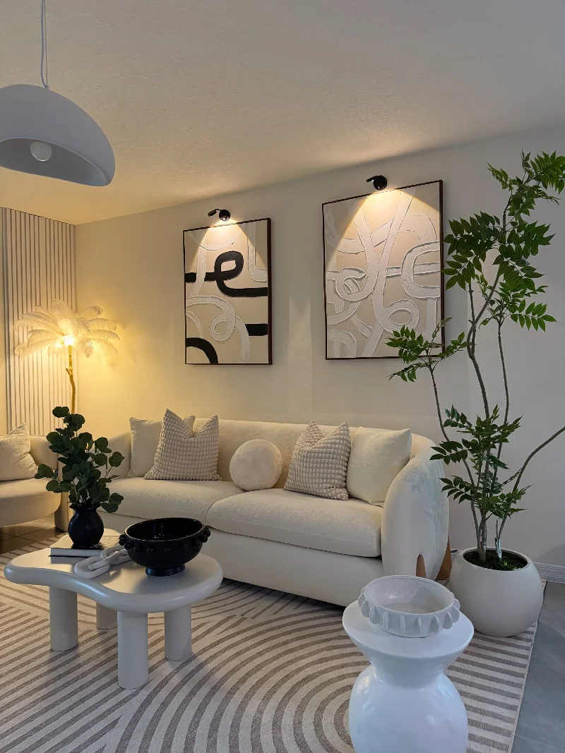 Curved Cream Sofa with Abstract Wall Art and Sculptural White Tables
