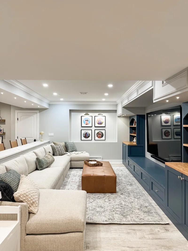 Custom Slate Blue Built-in Entertainment Unit with Tan Leather Ottoman and Cream Sectional Sofa