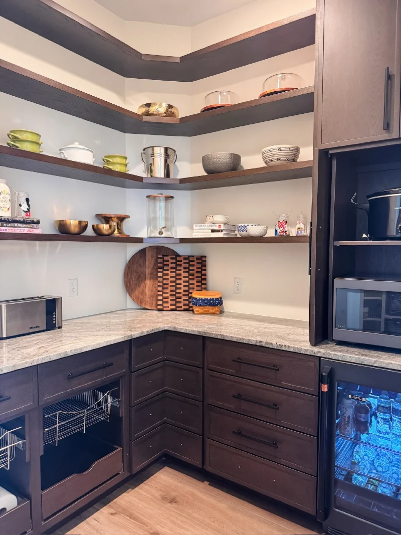 Dark Wood Pantry Corner with Wraparound Shelves, Cutting Boards, and a Beverage Fridge