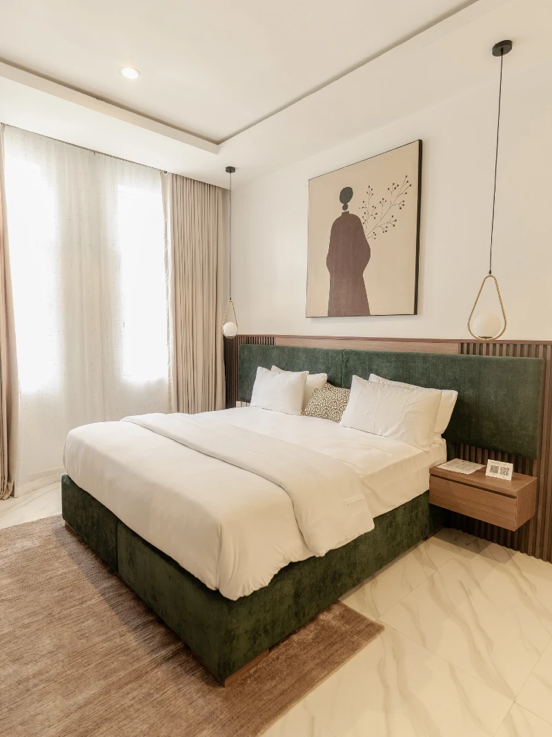Emerald Velvet Bed with Floating Pendant Lights and Minimal Art Frame Wall in Soft Neutral Bedroom