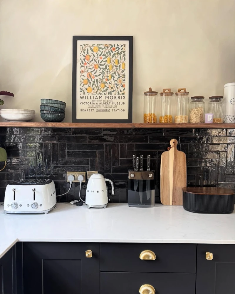 Glossy Black Subway Tile Kitchen Wall with Warm Wood Shelf and Brass Hardware Accents