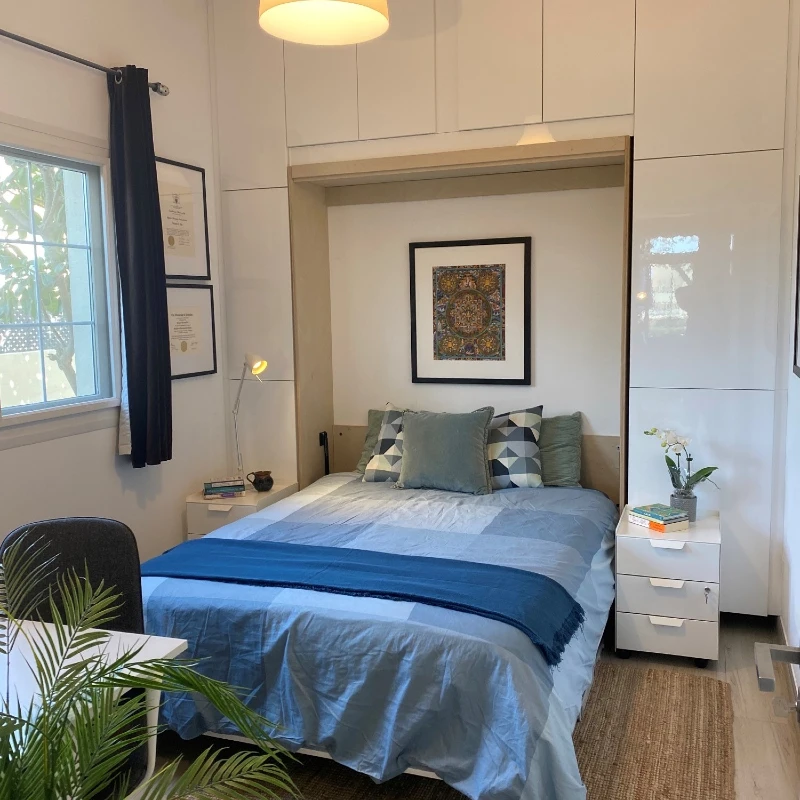 Glossy White Minimalist Wall Units with Blue Patchwork Linens and Framed Mandalas