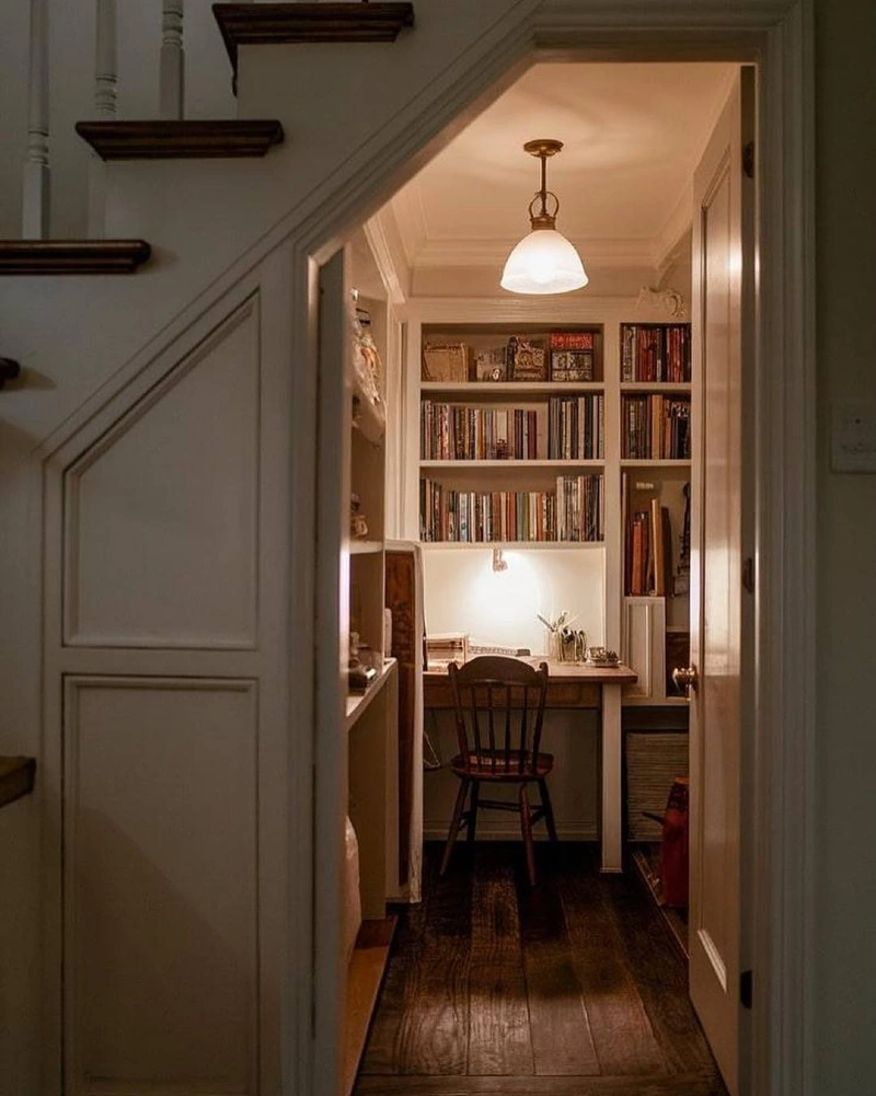 Hidden Under-Stairs Office with White Built-In Bookshelves and Vintage Wooden Chair