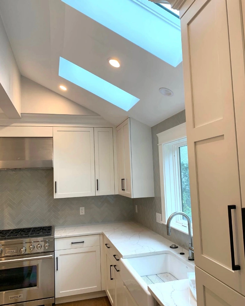 Integrated Skylights with White Shaker Cabinets and Gray Herringbone Backsplash