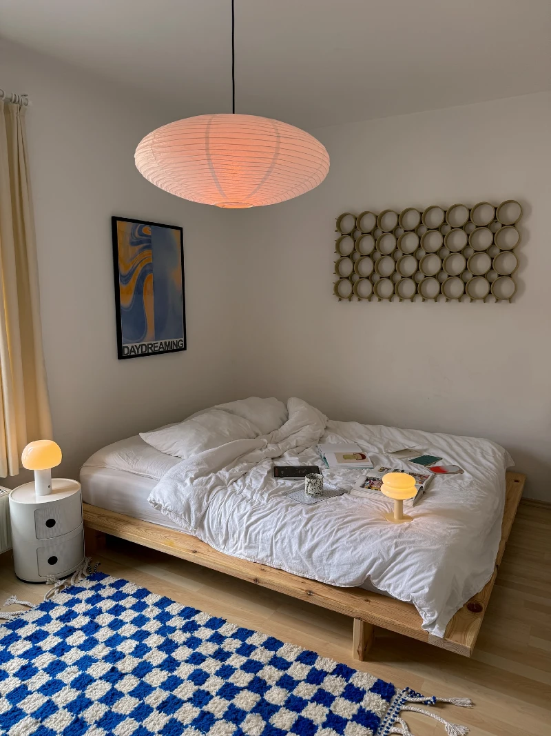 Low Wooden Platform Bed with Playful Blue Check Rug and Warm Paper Pendant Light