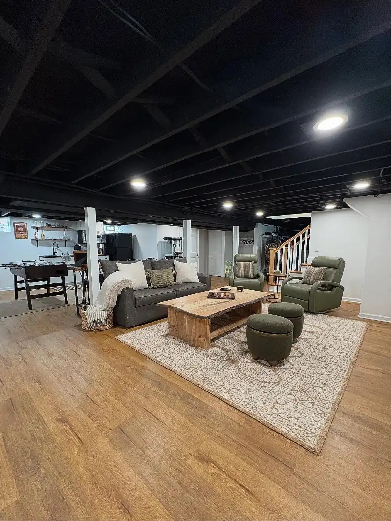 Matte Black Exposed Joist Ceiling with Olive Green Recliners and Live-Edge Wooden Coffee Table