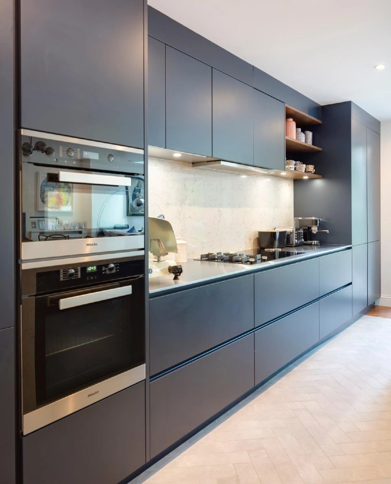 Matte Charcoal Handleless Cabinetry With Integrated Steel Ovens and White Quartz Backsplash