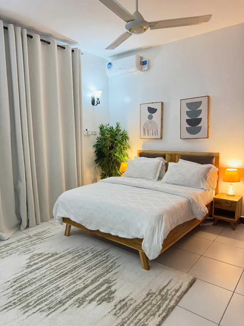 Minimal White Bed with Wooden Frame and Geometric Wall Art in Bright Apartment Bedroom