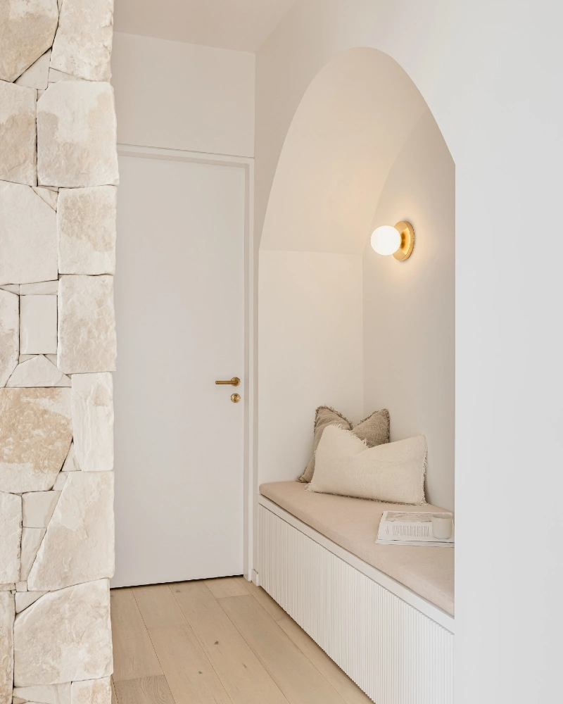 Minimalist Arched Seating Nook with Fluted Bench Base and Brass Sconce
