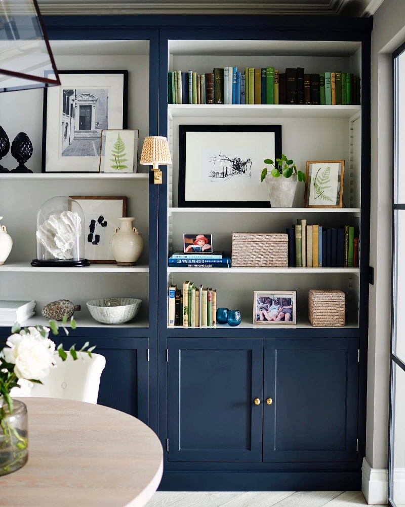 Navy Built In Bookcase with Botanical Art, Woven Boxes, and Brass Knobs