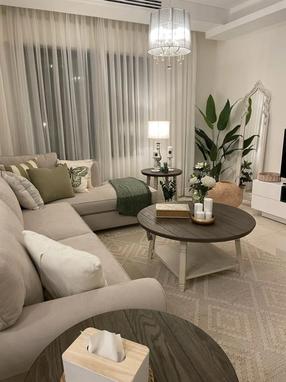Neutral Sectional Living Room with Round Coffee Tables and Crystal Chandelier Glow