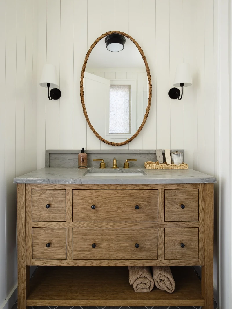 Oak Vanity with Grey Marble Countertop, Woven Oval Mirror, and Shiplap Walls