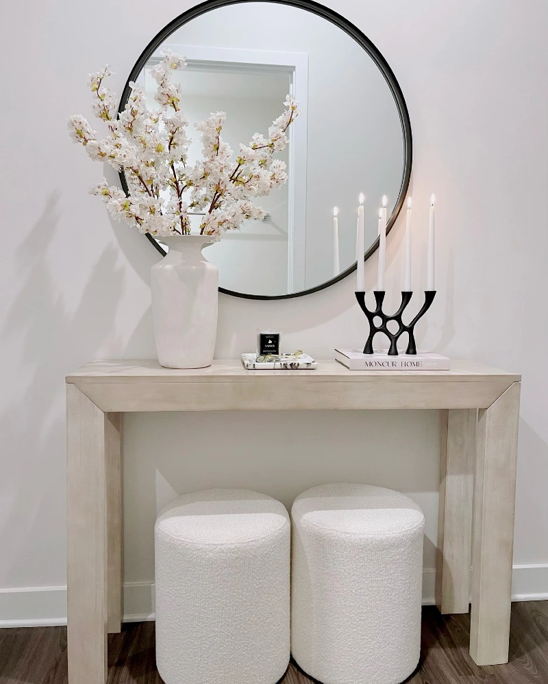Pale Wood Console with Round Black Mirror, Blossom Branches, and BouclΓ© Stools