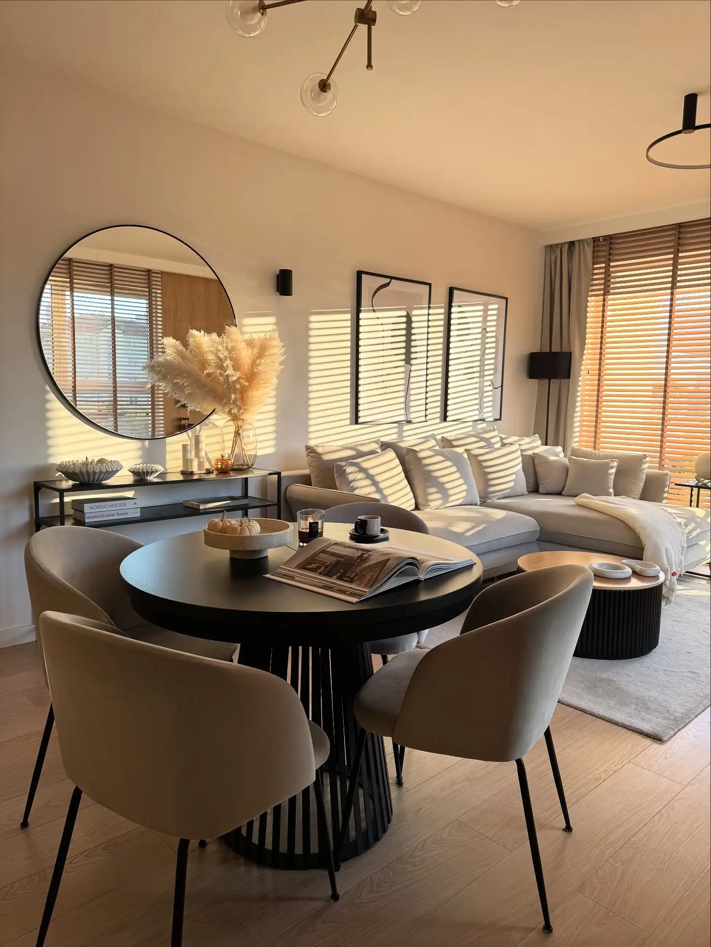 Round Black Dining Table with Beige Chairs Beside Soft Neutral Living Room