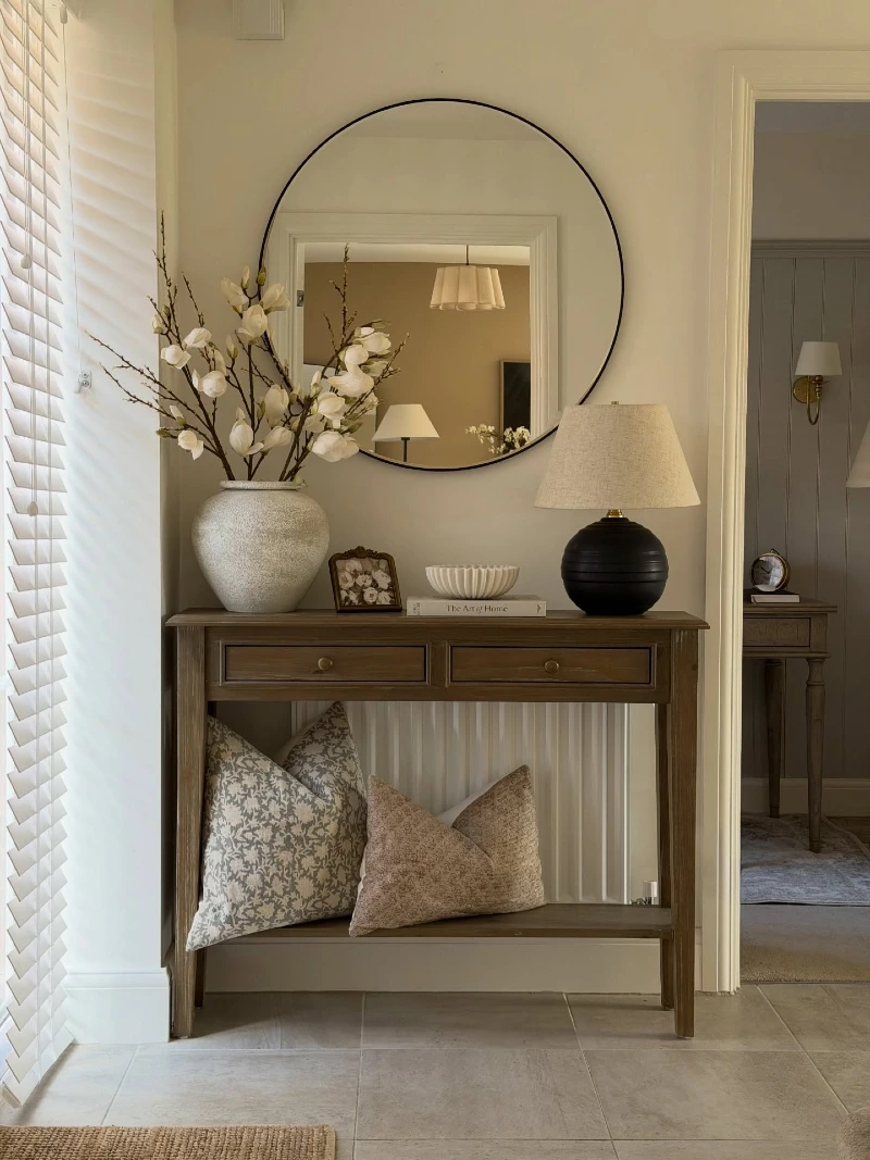 Round Black Mirror with Magnolia Branches, Ribbed Bowl, and Patterned Pillows