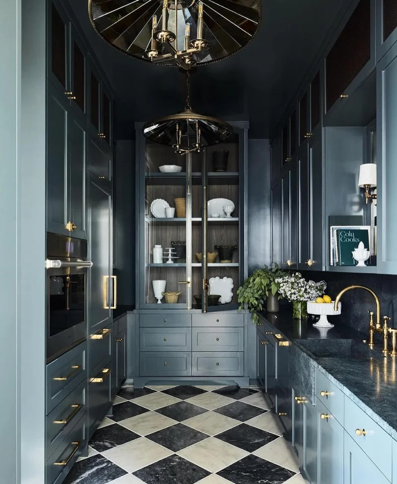 Slate Blue Galley Cabinetry With Harlequin Marble Floors and Brass Umbrella Pendants