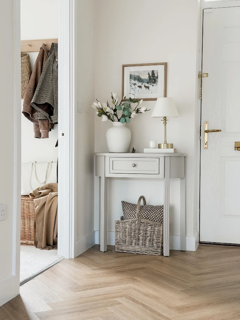 Small Gray Console with Brass Lamp, White Vase, and Woven Basket Storage