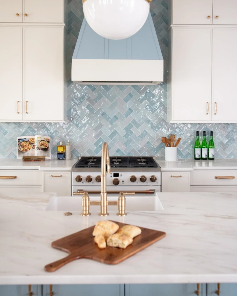 Soft Blue Herringbone Backsplash with Brass Faucet and White Island Centerpiece