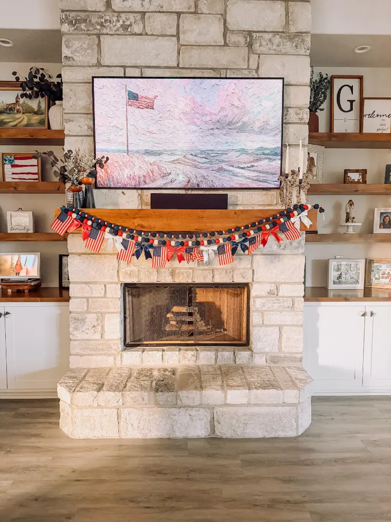 Stone Fireplace with Wood Mantel, Patriotic Garland, and Layered Family Shelves