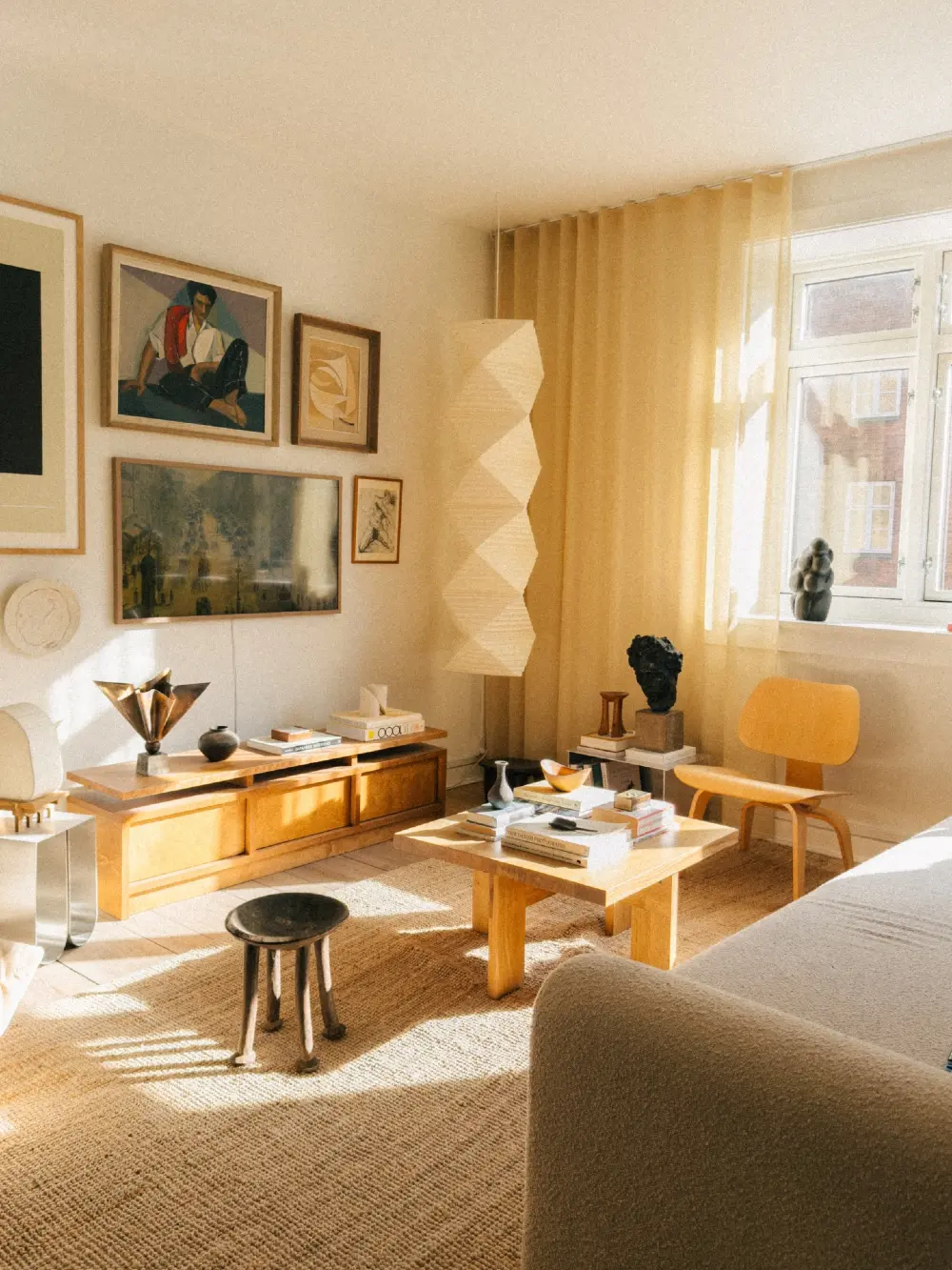 Sunlit Wooden Living Room with Sculptural Lighting and Warm Neutral Gallery Wall