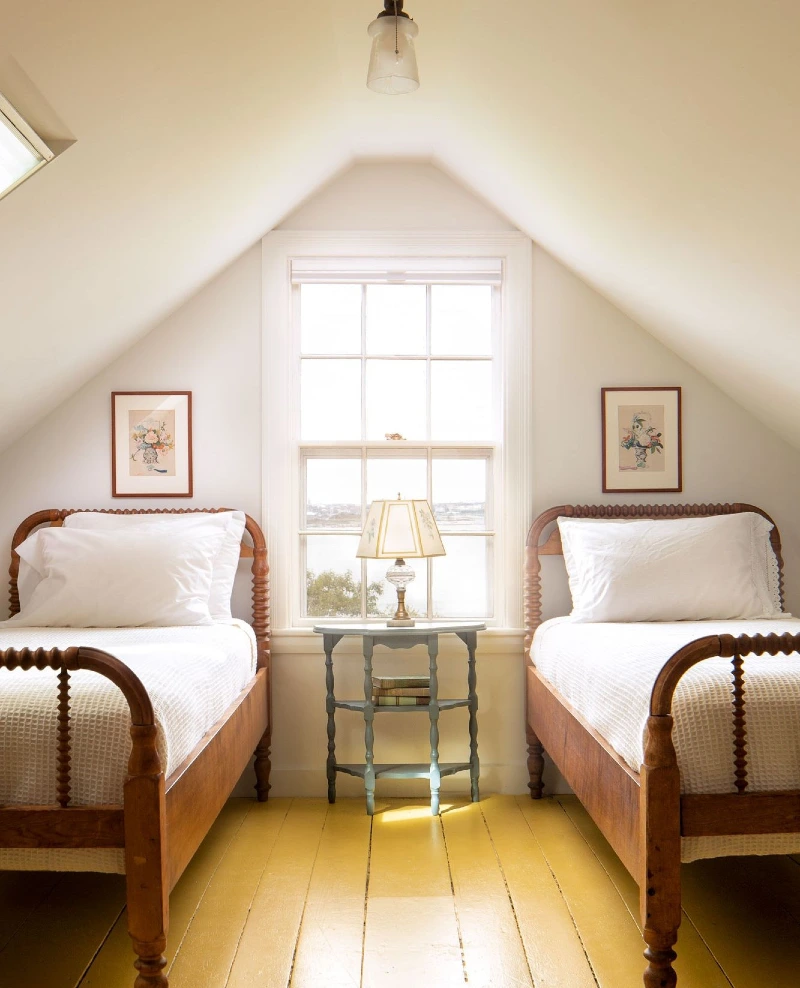 Symmetrical Spindle Twin Beds with Yellow Plank Floors and Blue Accent Table