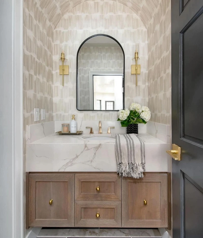 Thick Marble Apron Vanity with Arched Black Mirror and Patterned Wallpaper Alcove