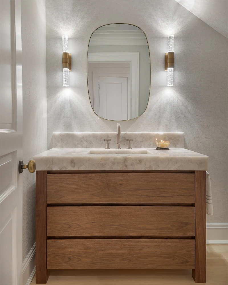 Thick Onyx Countertop with Integrated Basin, Flat-Panel Walnut Drawers, and Acrylic Cylinder Sconces