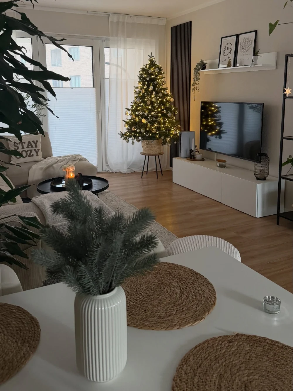Warm Holiday Living Room with Lit Christmas Tree and Minimal White Media Console