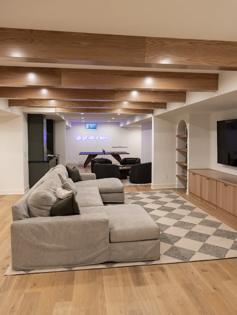 Warm Wood Ceiling Beams with Checkerboard Area Rug and Double-Chaise Gray Sectional