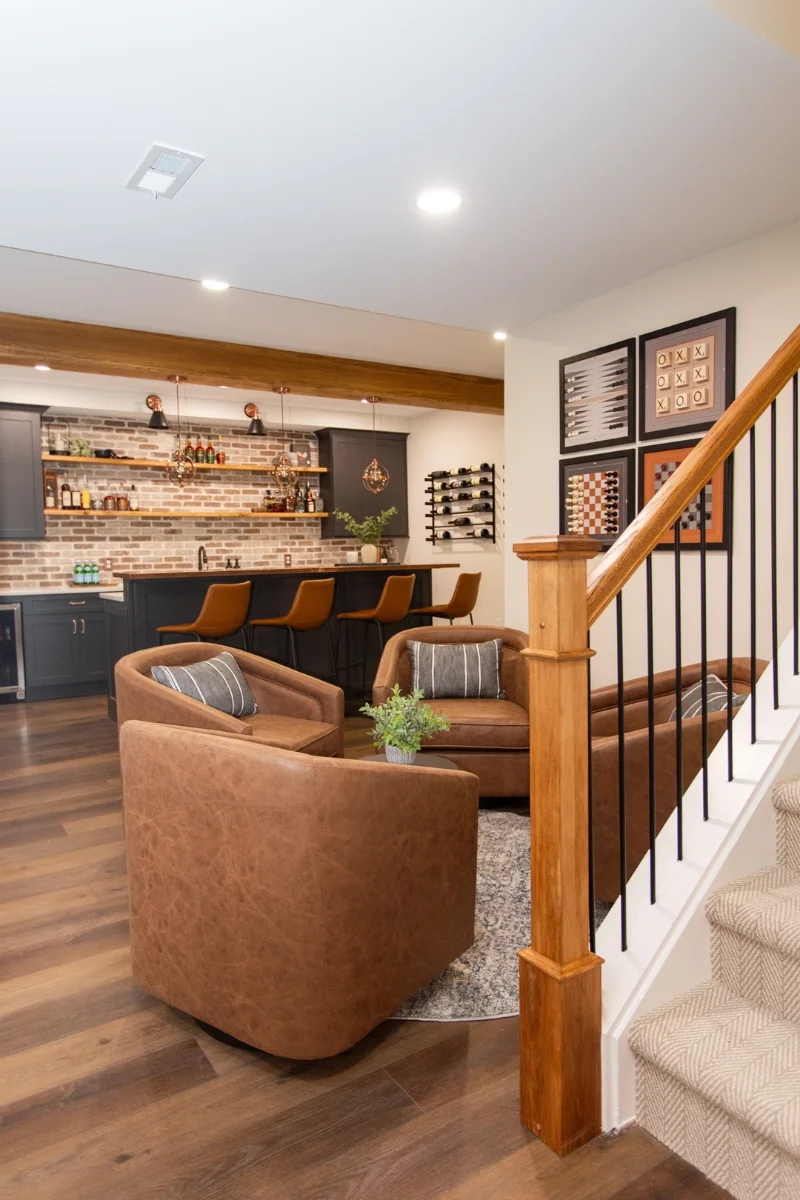 Weathered Brick Wet Bar Accent Wall with Cognac Leather Tub Chairs and Timber Staircase Post