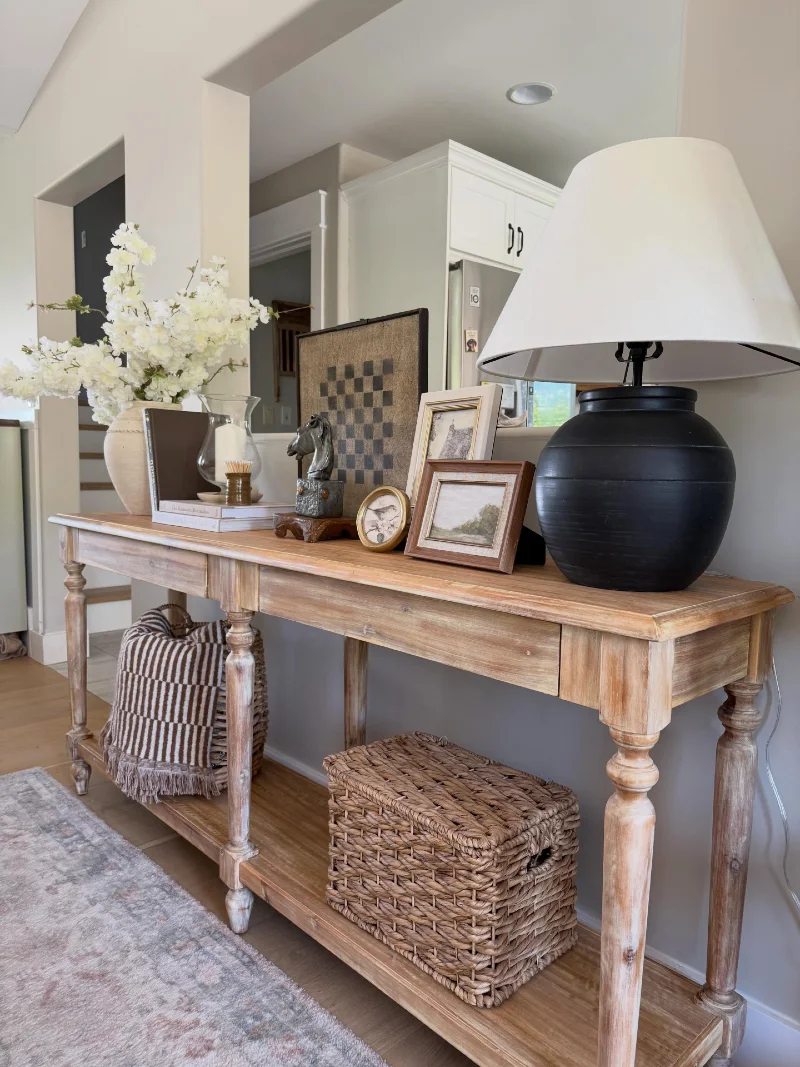 Weathered Wood Console with Black Lamp, Woven Baskets, and Vintage Frames