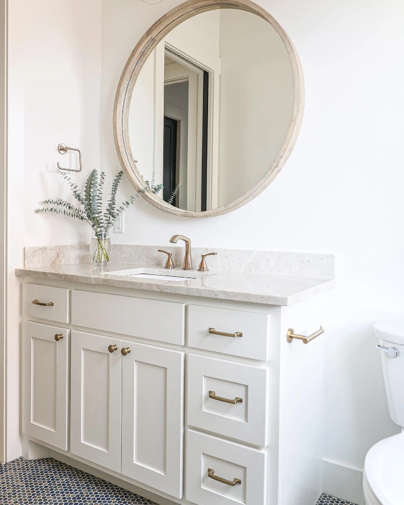 White Shaker Vanity with Beige Granite Countertop and Oversized Circular Wood Mirror