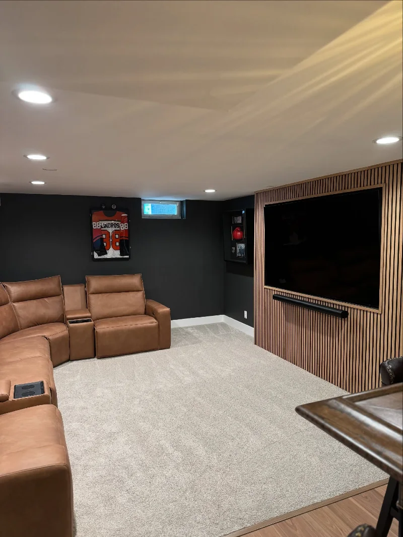 Wood Slat Media Wall with Camel Leather Reclining Sectional and Charcoal Drywall