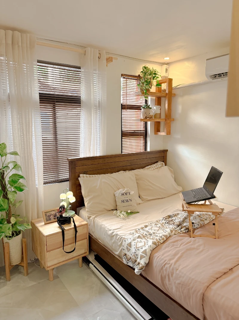 Wooden Bed Setup with Laptop Tray Table and Floating Plant Shelf in Bright Compact Bedroom