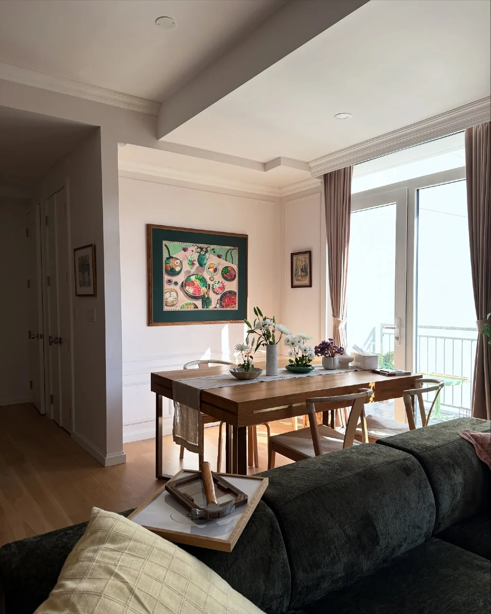 Wooden Dining Table with Framed Gallery Art and Sunlit Window Corner