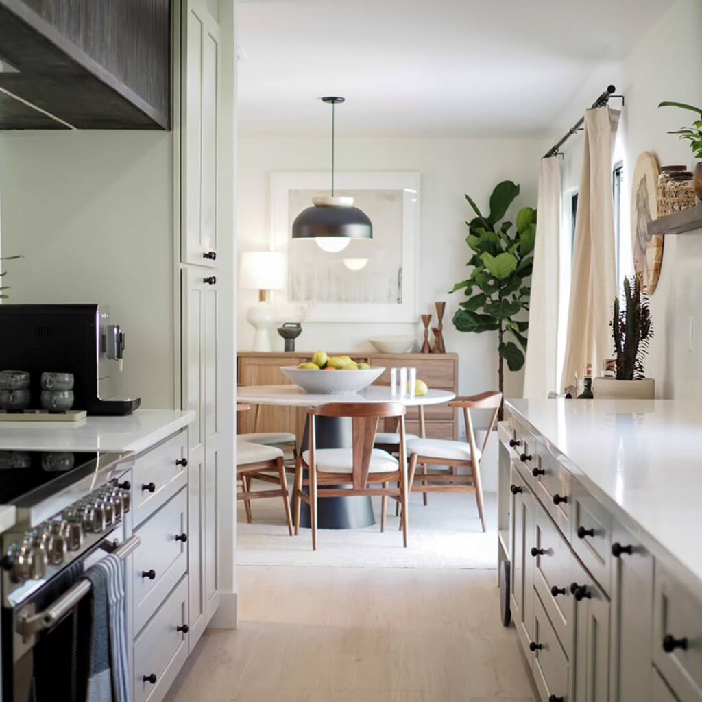 8. Pale Sage Galley Kitchen Opening Into a Light Wood Dining Room