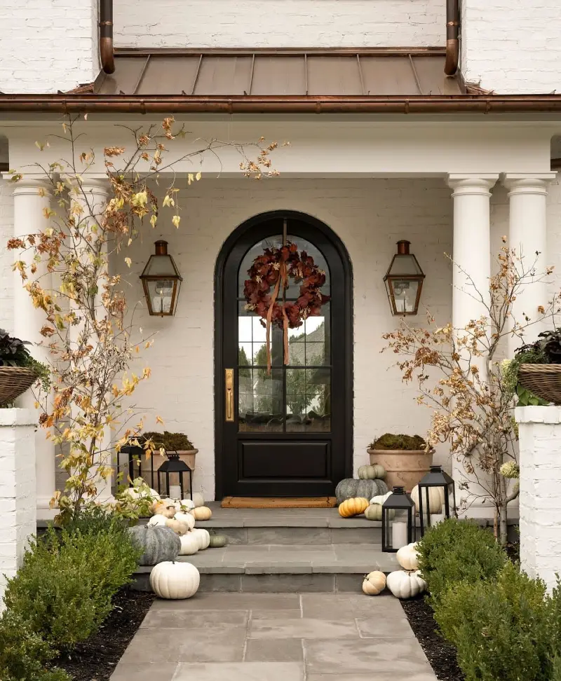 Arched Black Glass Door with Copper Lanterns, Muted Pumpkins, and Delicate Dried Saplings