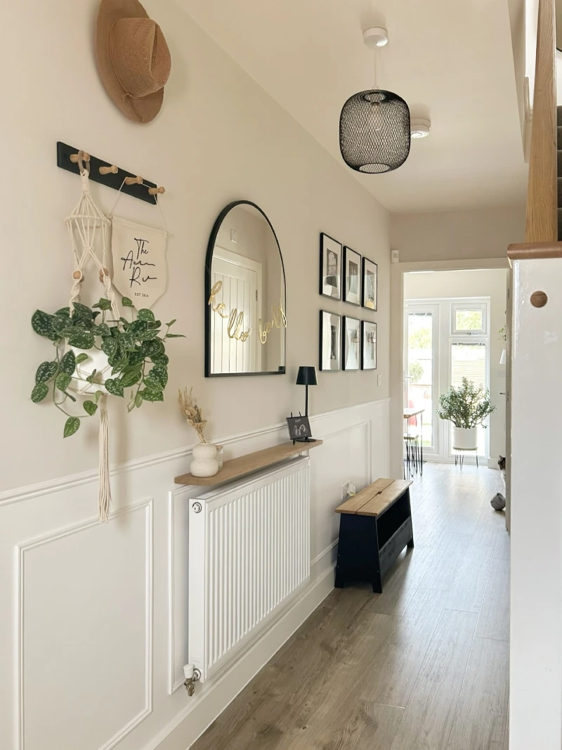 Arched black mirror above wooden radiator shelf with hanging macrame planter