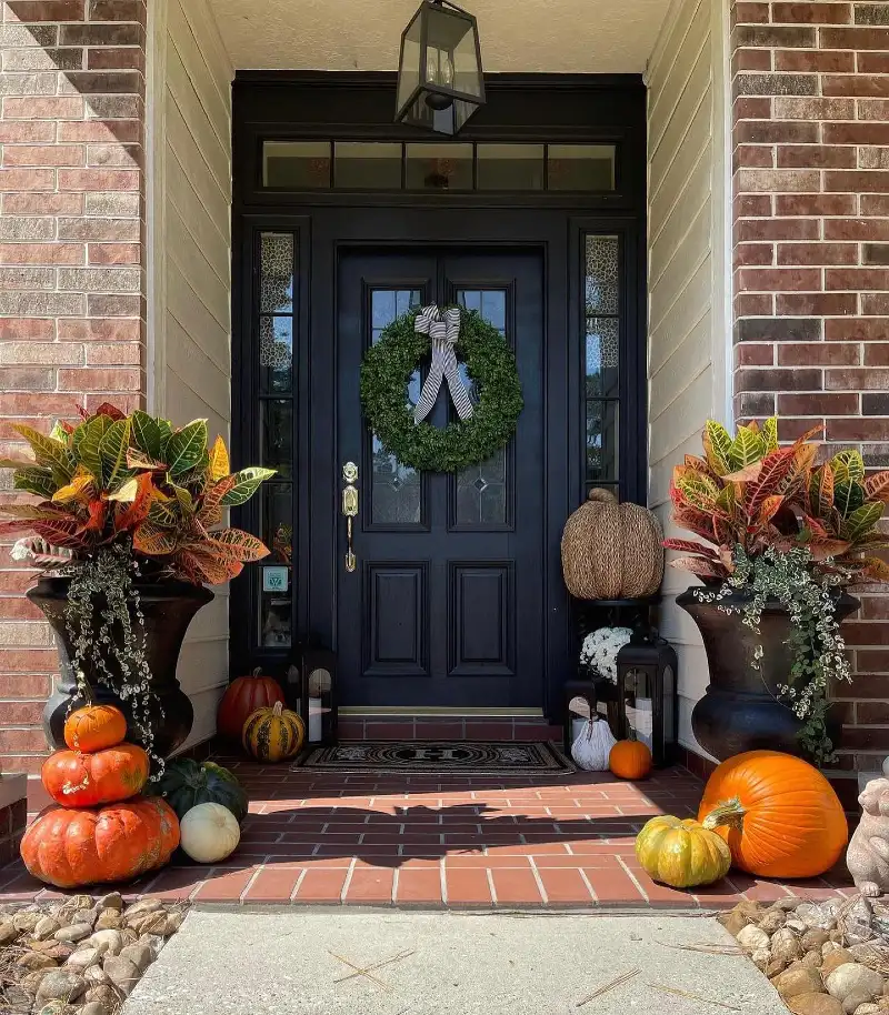 Black Front Door with Boxwood Wreath, Large Urn Planters, and Stacked Heirloom Pumpkins