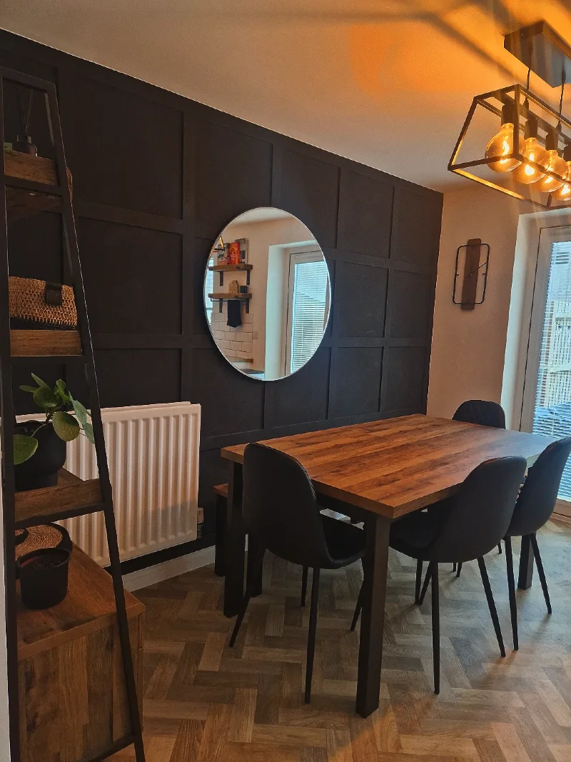 Black Grid Paneled Dining Wall with Frameless Round Mirror and Industrial Chandelier