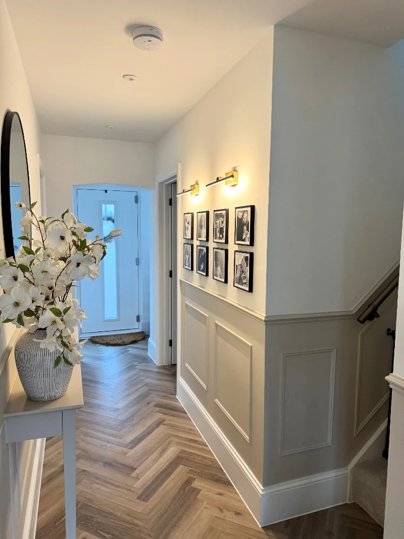 Brass Picture Lights and Black Grid Frames Above Greige Wainscoting Paneling
